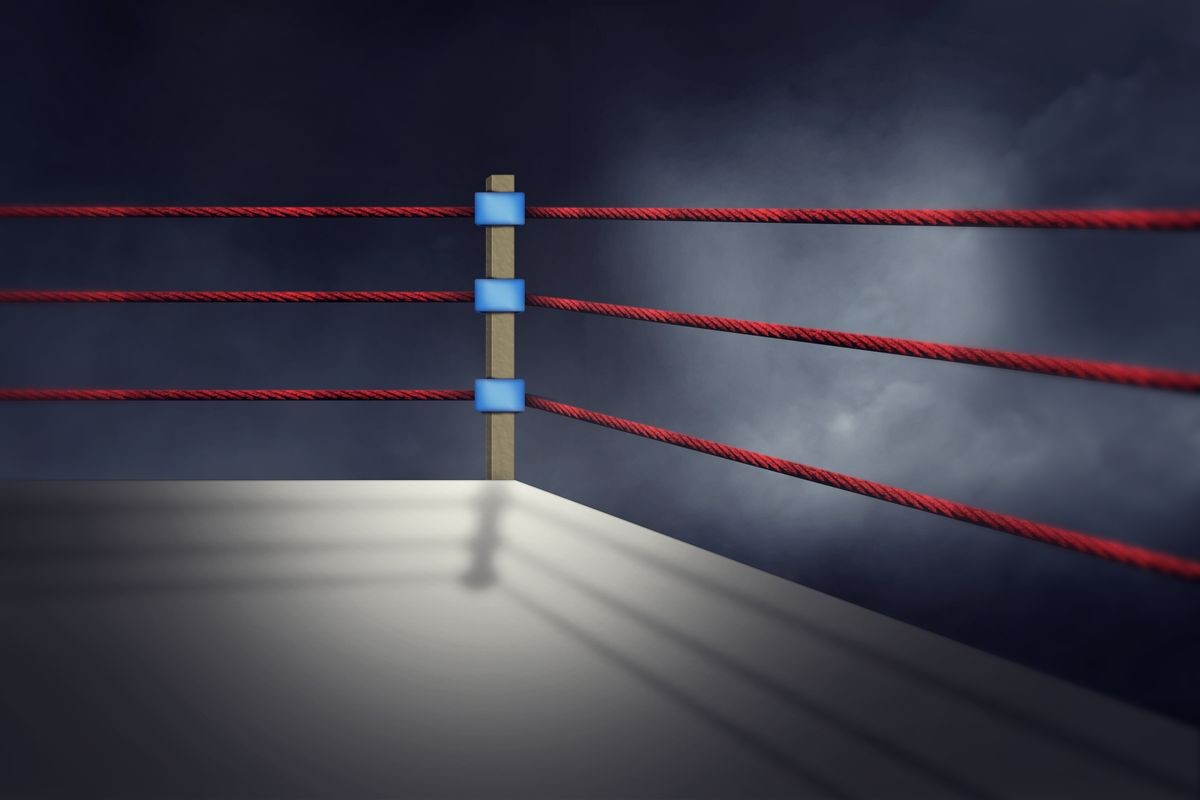 View of a regular boxing ring surrounded by red ropes spotlit by a spotlight